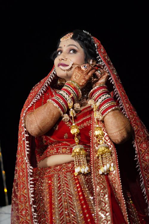 Free Stunning Indian bride in ornate red bridal outfit with intricate jewelry and henna, showcasing cultural elegance. Stock Photo