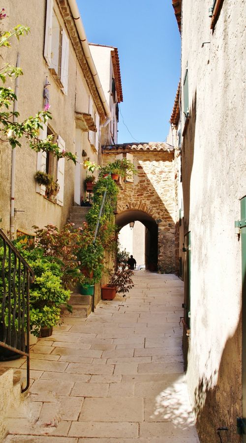 Free Picturesque narrow street in Gassin, Provence with stone architecture and lush greenery. Stock Photo