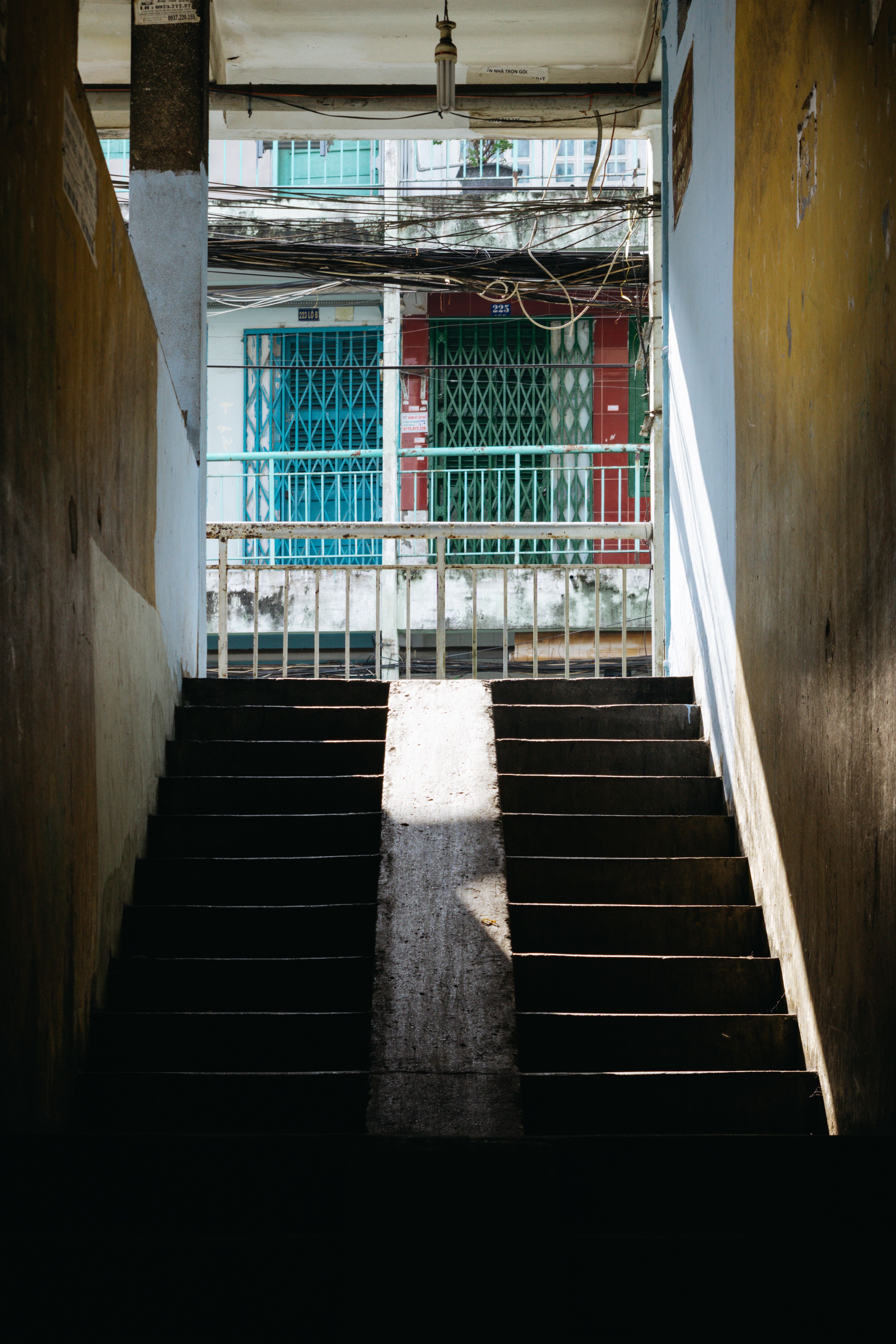 A staircase leading outdoors with sunlight casting dramatic shadows.