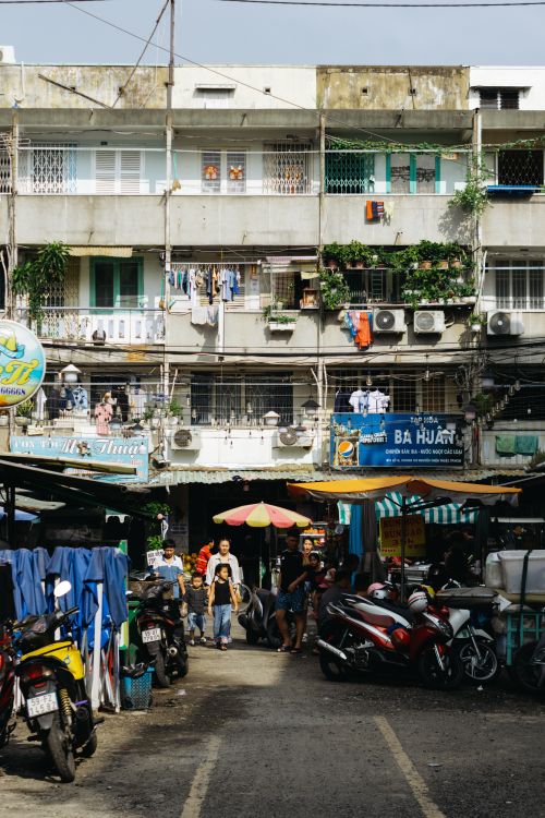 Free Asian street market with motorcycles and people in front of urban apartment building. Stock Photo