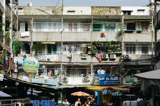 Colorful urban market scene with bustling crowd in front of a vintage apartment block.