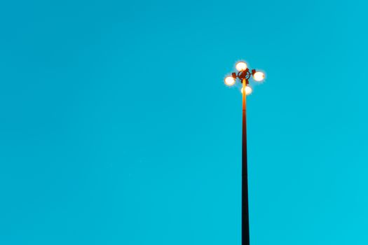 A tall streetlight stands against a bright clear blue sky creating a minimalist aesthetic.