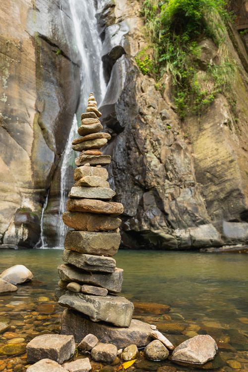 Free A tall stone cairn stands by a picturesque waterfall in Mandaram Nuwara, Sri Lanka. Stock Photo