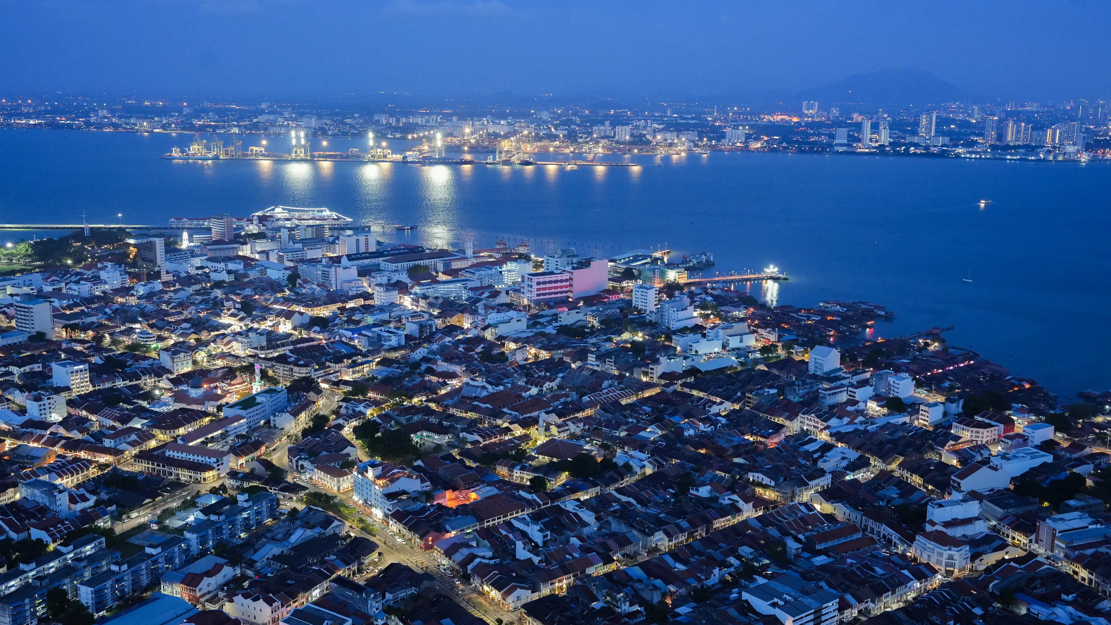 Captivating night aerial skyline of Penang, Malaysia, showcasing urban lights and sea view.