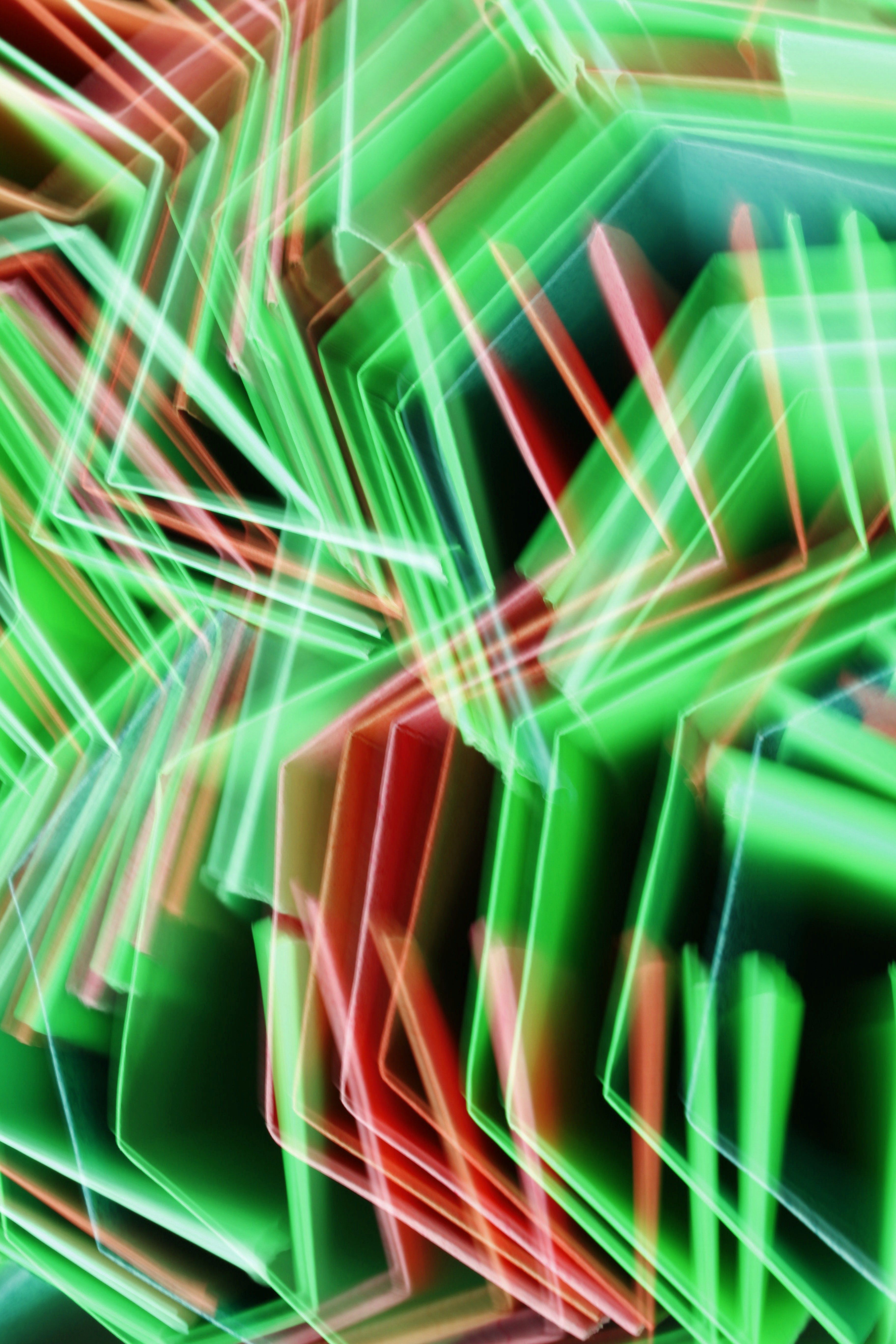 Vibrant abstract image of neon light patterns in green and red hues, creating dynamic movement.