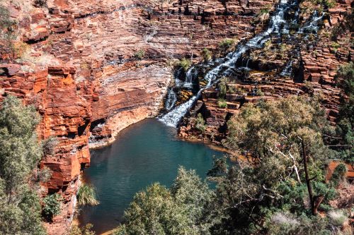 Free Beautiful waterfall cascading over red rock cliffs in Karijini National Park, Australia. Stock Photo