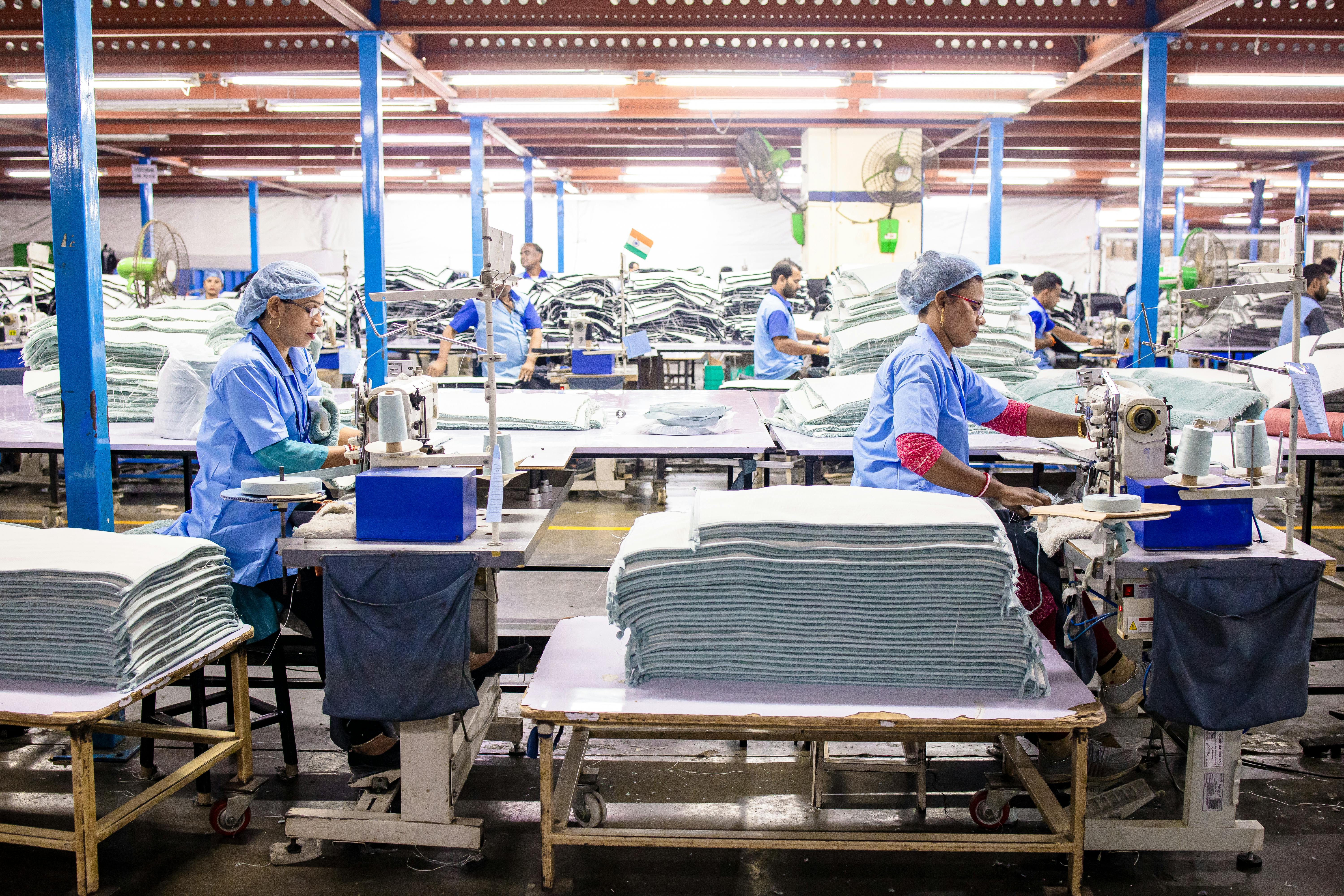Blue-collar workers in a textile factory sewing fabrics. Efficient industrial workplace.