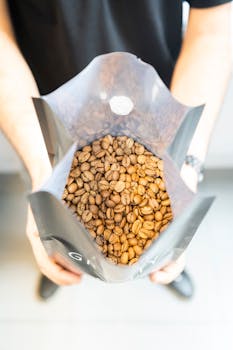 A close-up view of fresh coffee beans inside an open bag held by hands