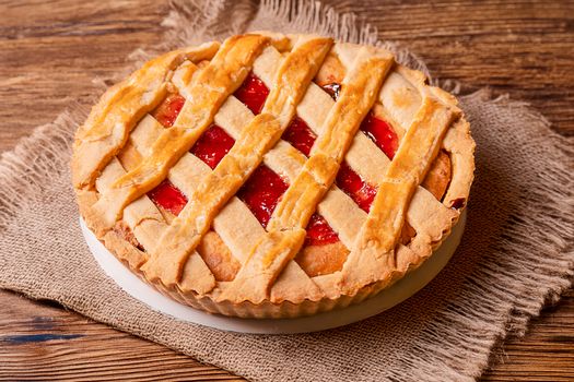 A mouthwatering strawberry lattice pie on a rustic wooden table in Lima, Perú.