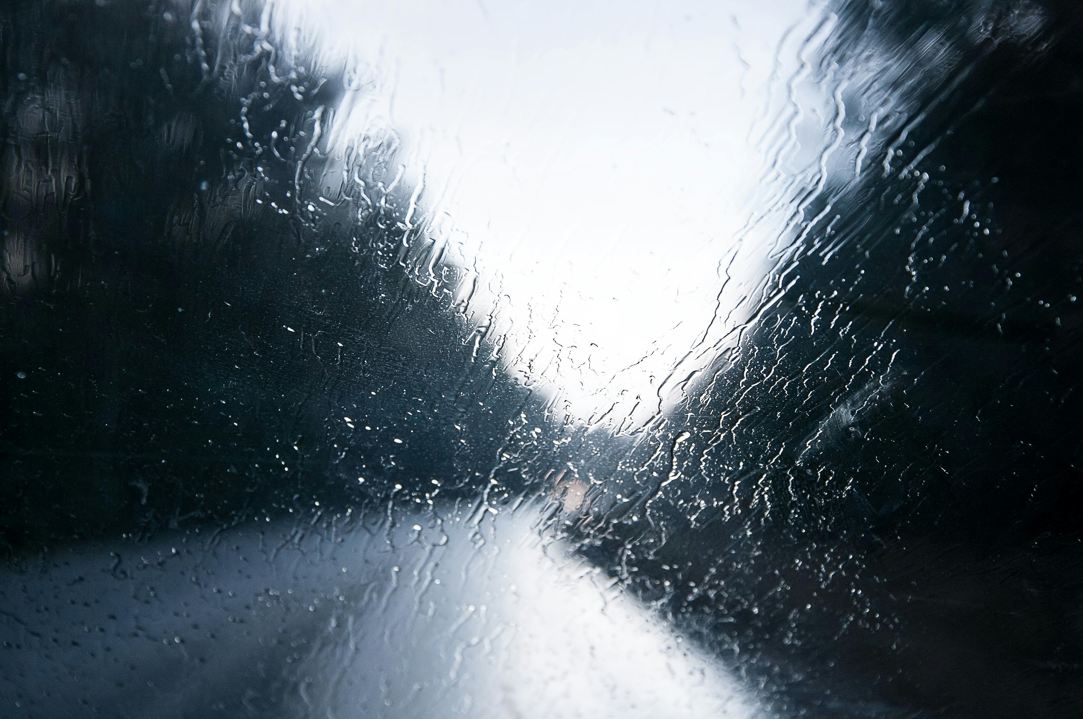 Artistic view through rainy car window on highway. Captures mood with blurred perspective.