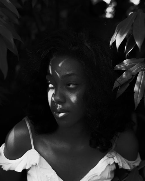 Free Dramatic black and white portrait of a woman amidst foliage, play of light and shadow. Stock Photo