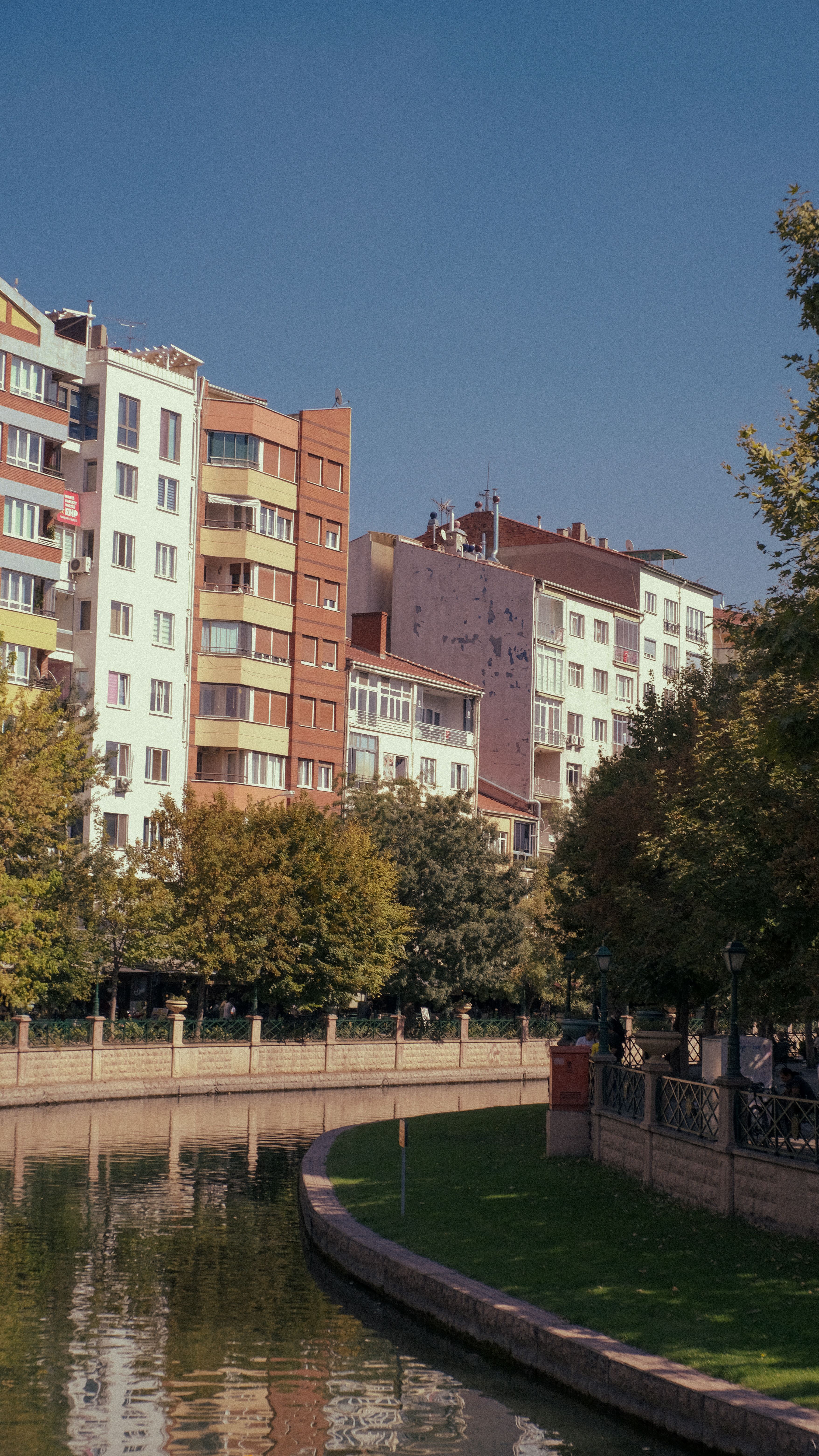 Scenic view of urban buildings reflecting on a canal on a sunny day.