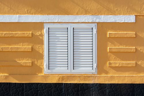 Free Close-up of a yellow wall with white shutters, minimalistic design and strong geometric patterns. Stock Photo
