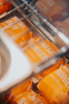 Close-up of cheeseburgers wrapped in orange packaging on a tray.