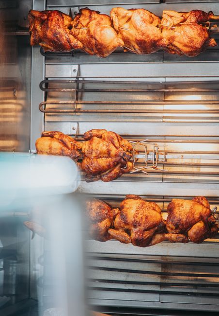 Mouthwatering rotisserie chicken cooked to perfection on a grill spit in a cozy indoor setting