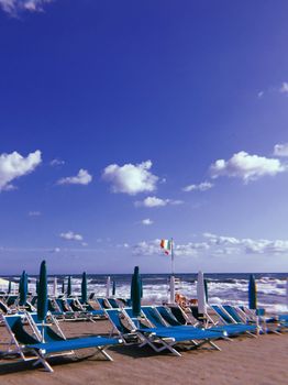 宁静的海滩上，躺椅面朝大海，天空蔚蓝