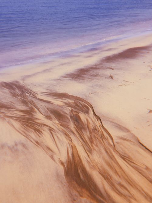 Free A tranquil beachscape showcasing captivating patterns in the sand during sunset. Stock Photo