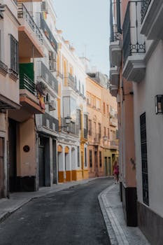 Explore the vibrant colors and historic architecture of a narrow street in Seville, capturing Spain's charm.
