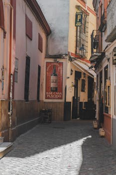 Discover a quaint alley in Sevilla, Spain, featuring classic Andalusian architecture and vintage signage.