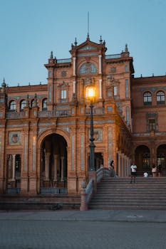 View of Plaza de España in Seville at twilight, showing its iconic architecture and classic lamp post.