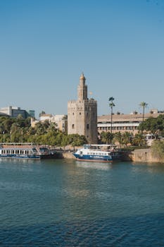 Torre del Oro tower beside the Guadalquivir River in Seville, Spain with riverboats.