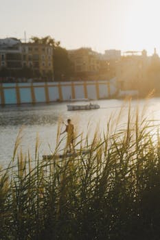 Adult paddleboarding at sunset on the Guadalquivir River with scenic cityscape of Seville, Spain