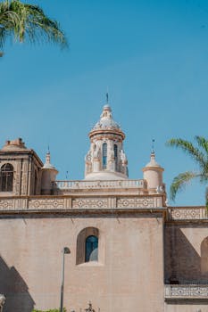 Beautiful historic building in Sevilla, Spain with clear blue sky and palm trees.