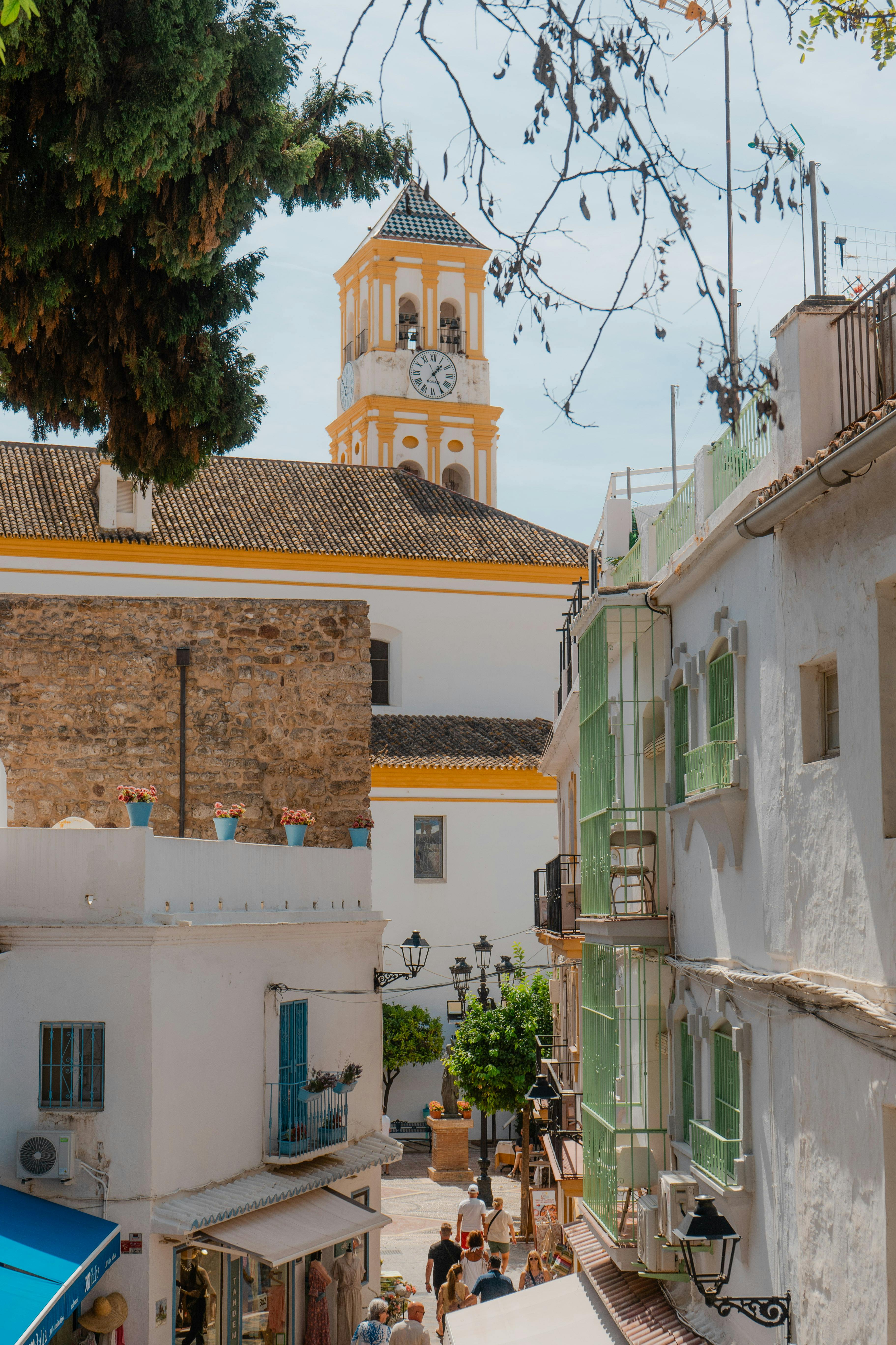 Sunny day in Marbella's old town with whitewashed buildings and clock tower.