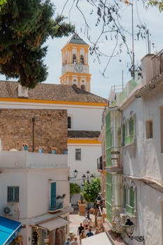 Sunny day in Marbella's old town with whitewashed buildings and clock tower.