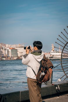 A person taking photos by the riverside in a city setting. Scenic urban photography scene.
