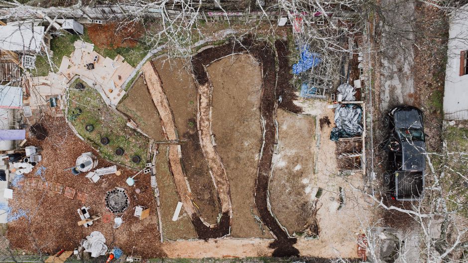 Aerial shot of a backyard construction site with various materials and earthworks. Aerial shot of a backyard construction site with various materials and earthworks.