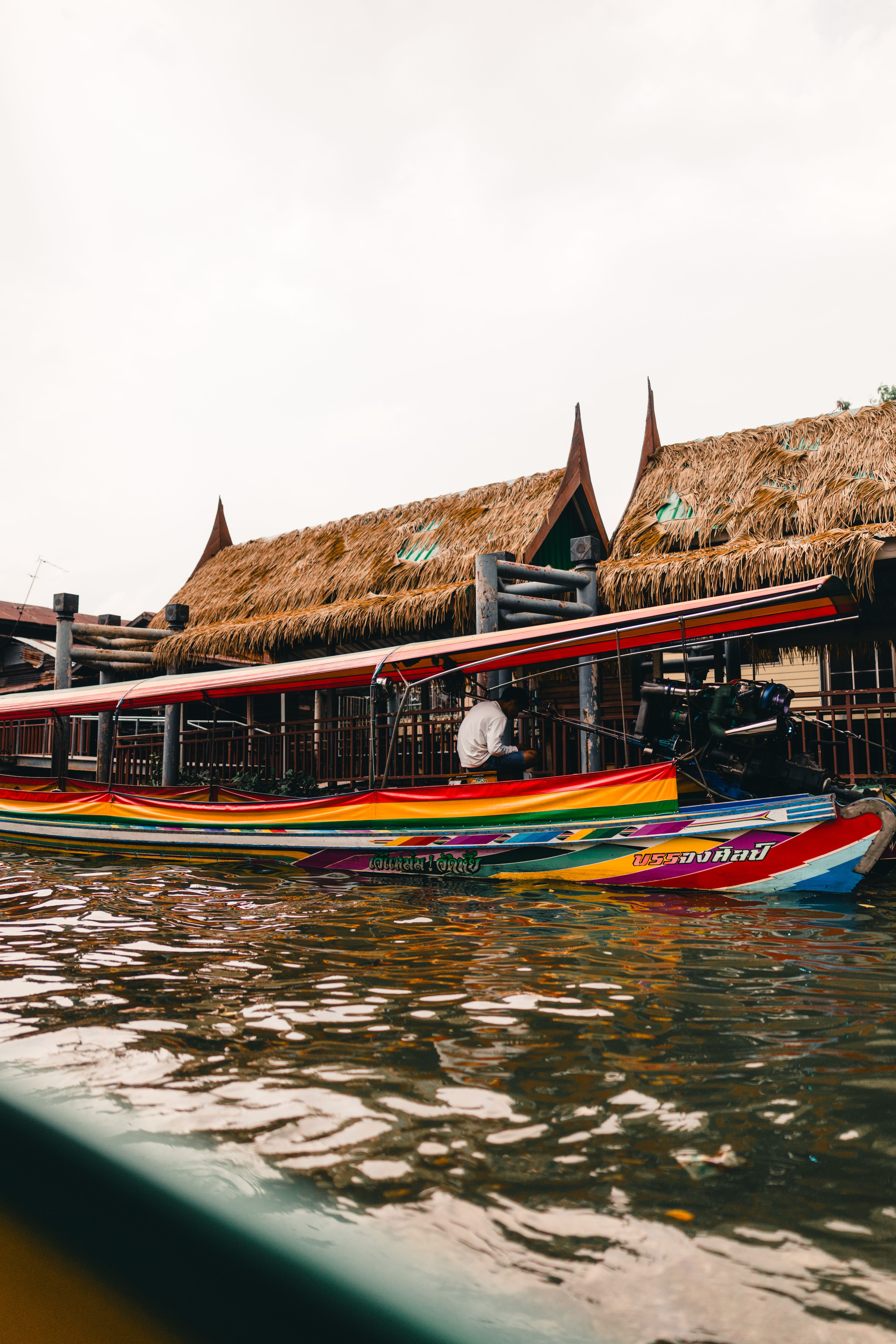 A longtail boat on a river canal near a traditional floating market.