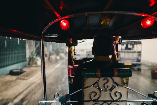 View from a tuk-tuk in rainy Bangkok, capturing the vibrant city life and local transportation.