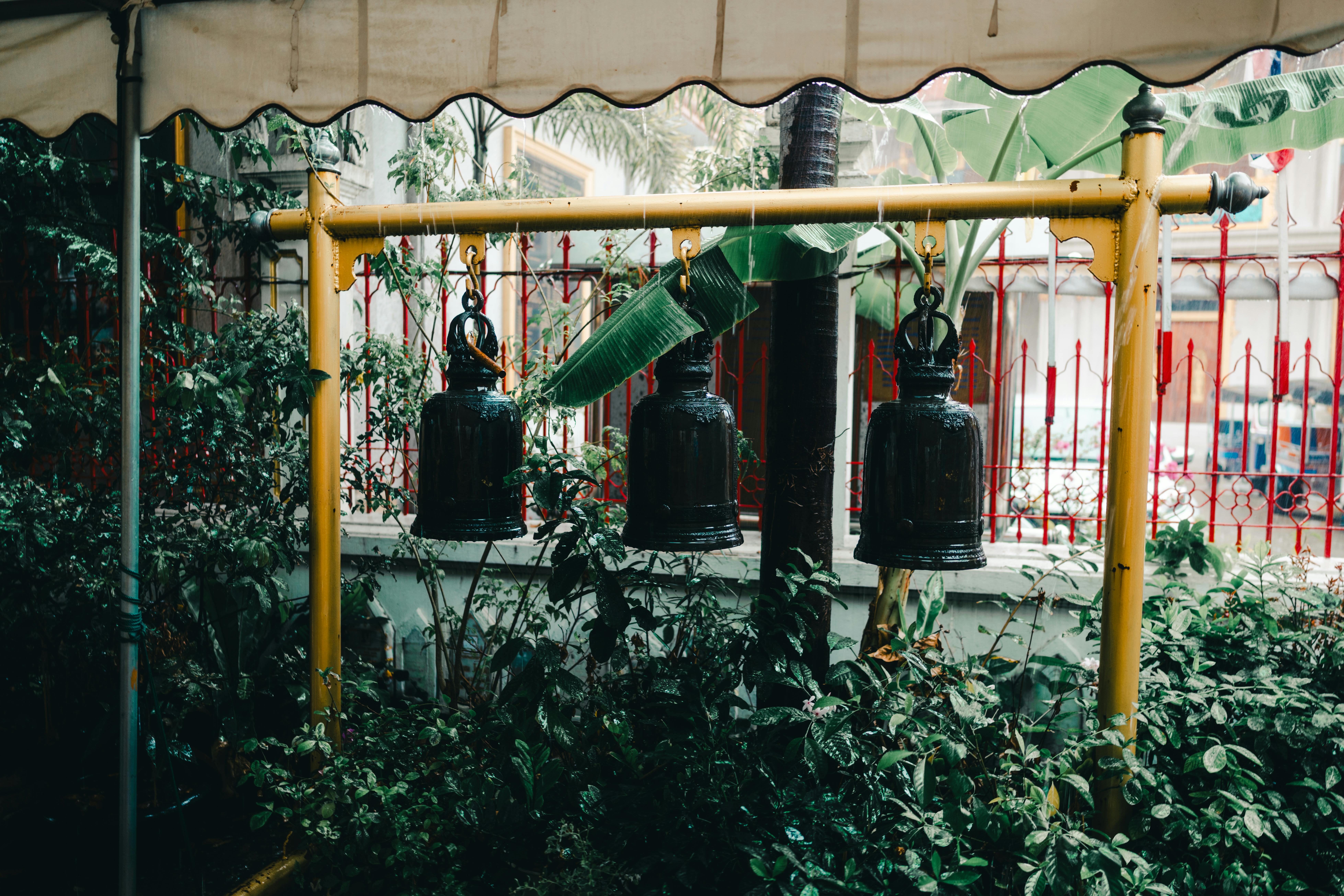 Kostnadsfria Traditionella klockor som hänger i en lummig trädgård i Bangkok, Thailand, skapar en lugn atmosfär. Stock foto