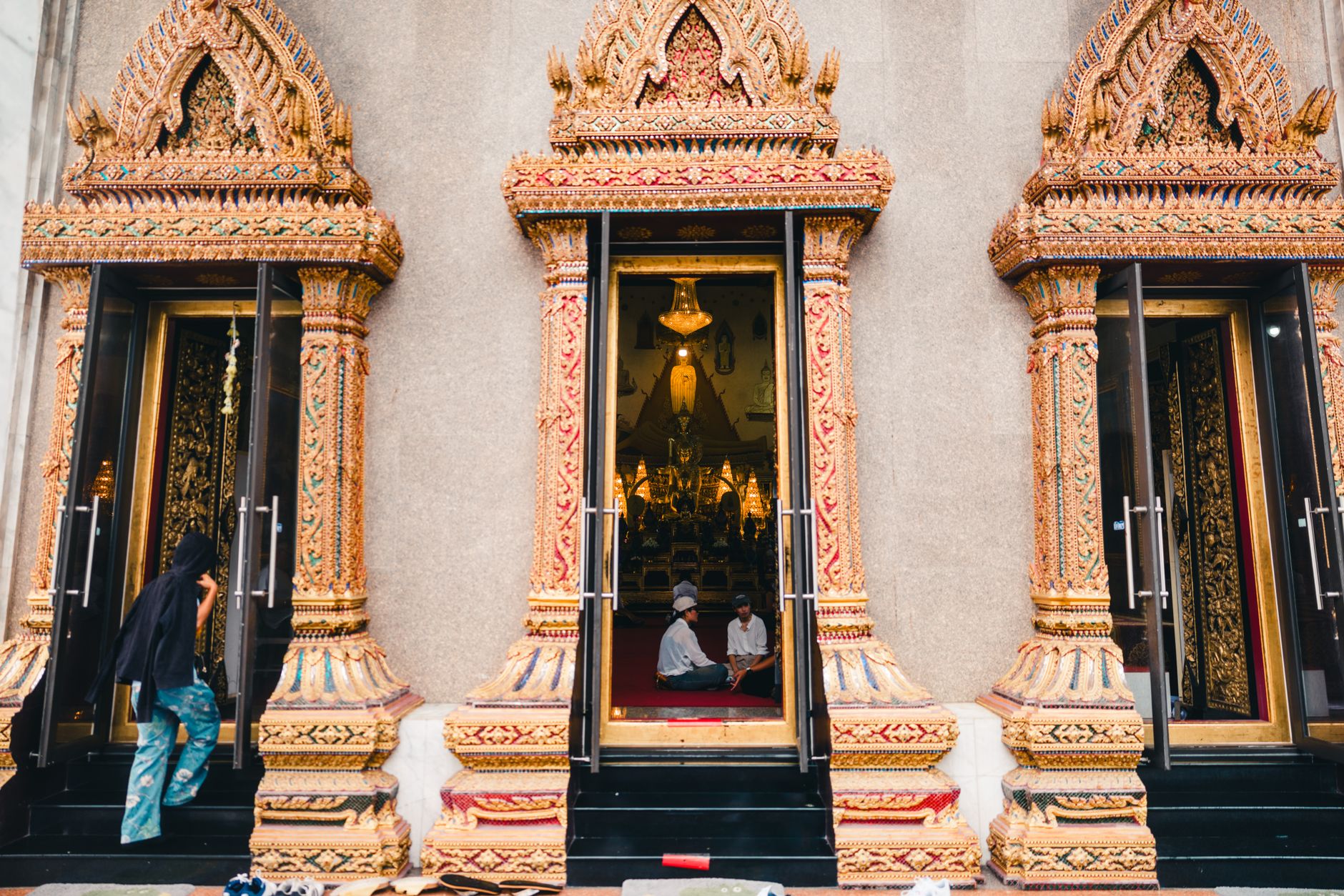 Hands performing a wai greeting in front of a temple
