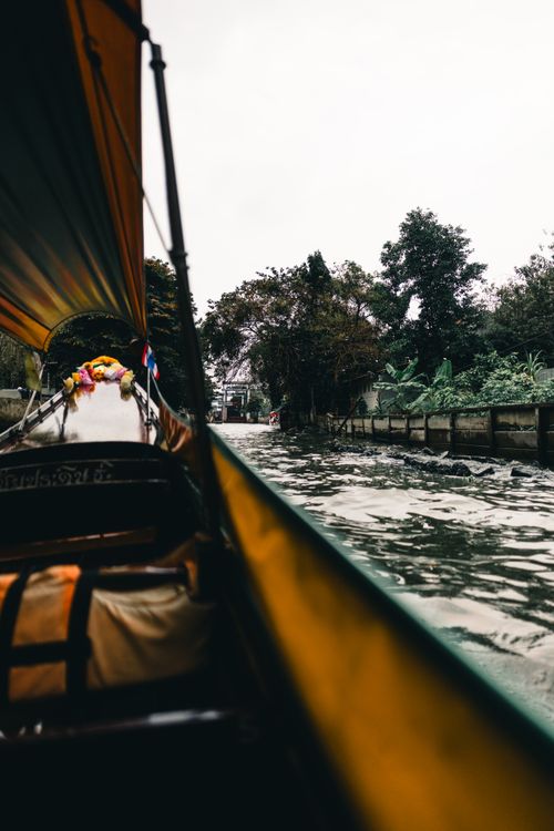 Free Experience the vibrant Bangkok canals on a traditional boat ride, showcasing lush greenery and serene waterways. Stock Photo