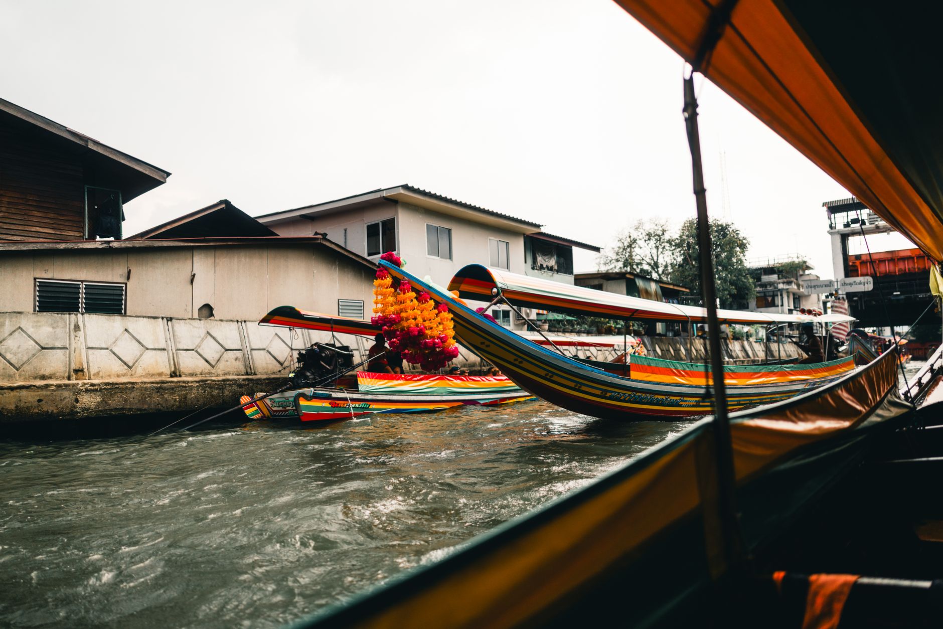 Longtail boats on a canal in Thonburi with wooden houses on stilts