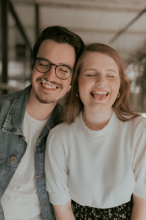 Free Joyful young couple sharing a moment of laughter with ice cream indoors, signifying happiness and relationship. Stock Photo