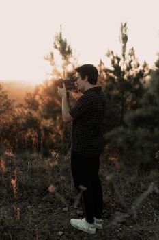 Man photographing sunset in forest, embracing outdoor exploration.