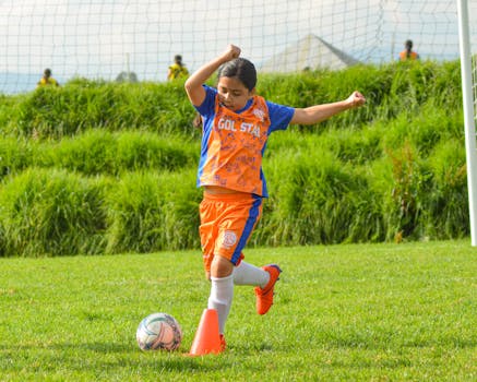 Young girl practicing soccer outdoors on a sunny day.