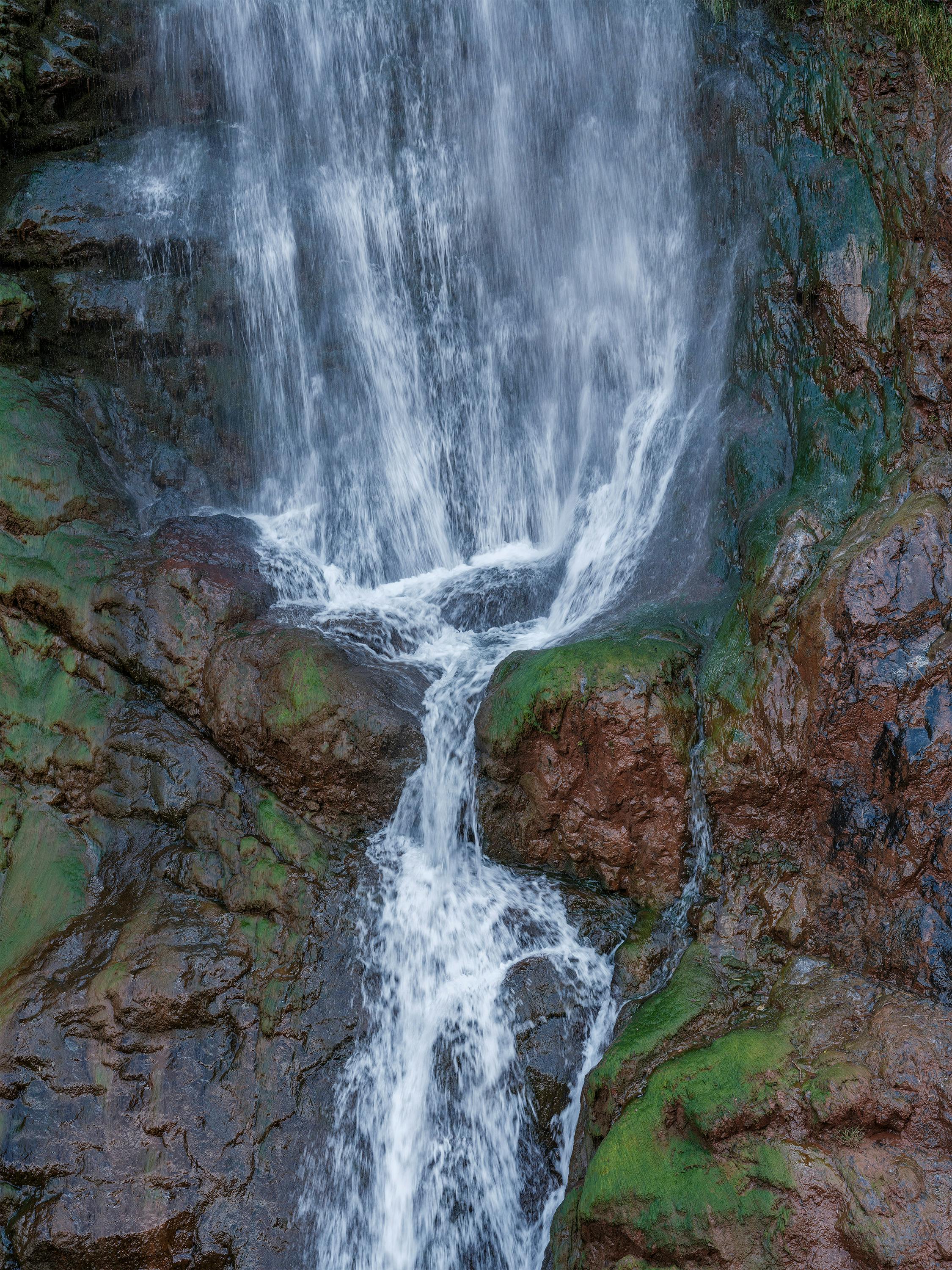 Close-up of a stunning waterfall cascading over moss-covered rocks in a natural setting.