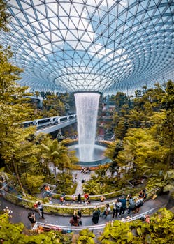 Stunning indoor waterfall surrounded by lush greenery at Jewel Changi Airport, Singapore.