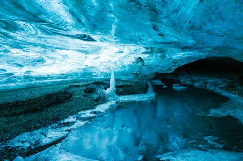 Free Explore the stunning beauty of a blue ice cave with reflective icy waters. Stock Photo