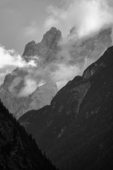 Black and white photo of Dolomite peaks in Toblach, Italy, partially covered in mist.