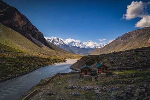 Free Stunning view of Kargil Valley, two cabins by river, surrounded by majestic Himalayan peaks. Stock Photo