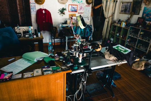 A detailed view of a tailor's workshop in Phuket, showcasing a sewing machine and multiple fabrics.