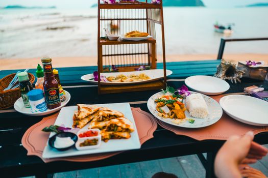 Enjoy a vibrant Thai meal by the beach in Phuket, Thailand, capturing the essence of local culinary delights.