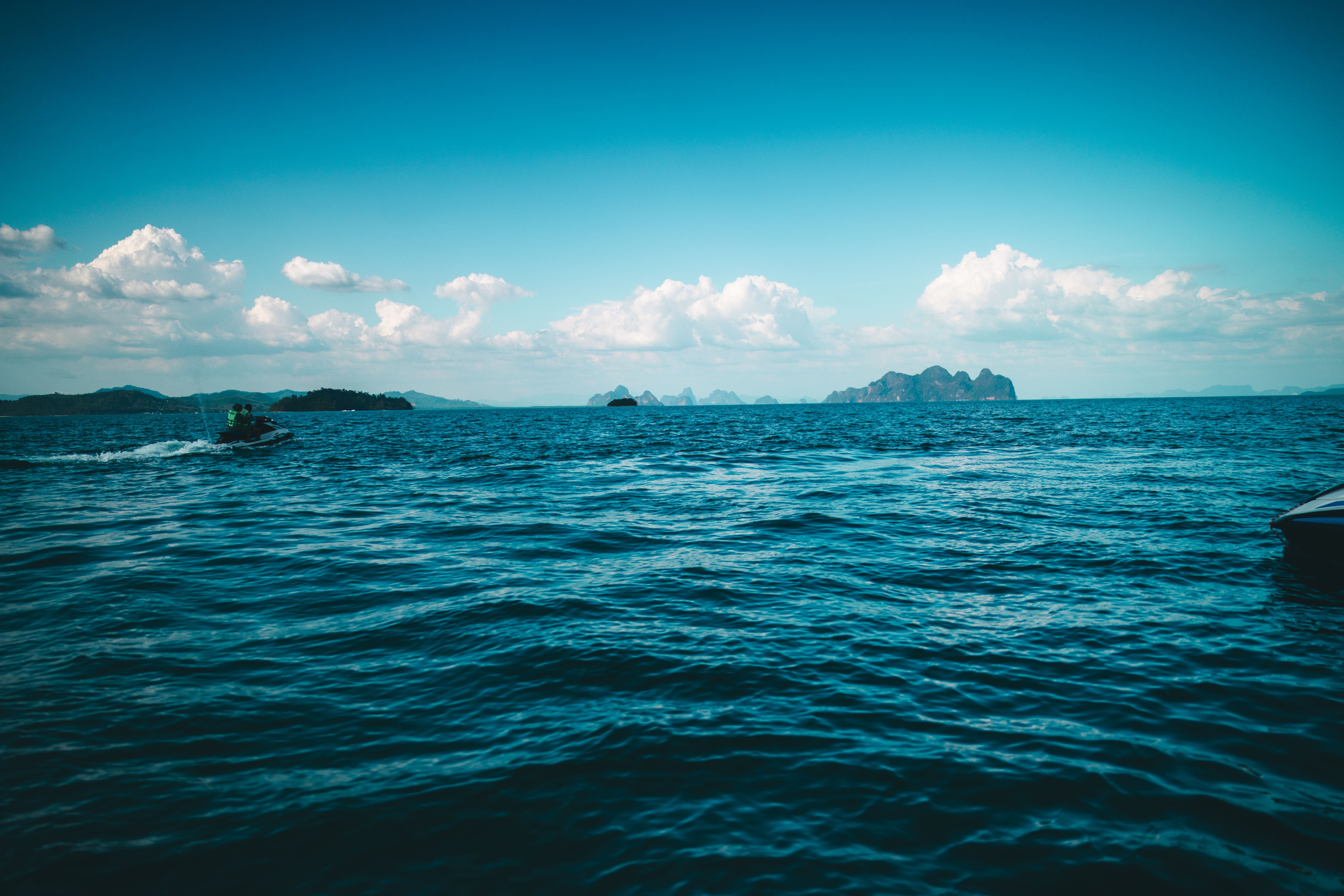 Vibrant seascape with distant islands and a jet ski in Phuket, Thailand.