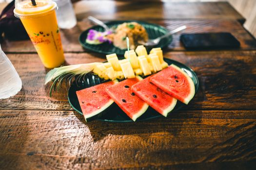 Fresh tropical fruits including watermelon and pineapple on a rustic table in Phuket.