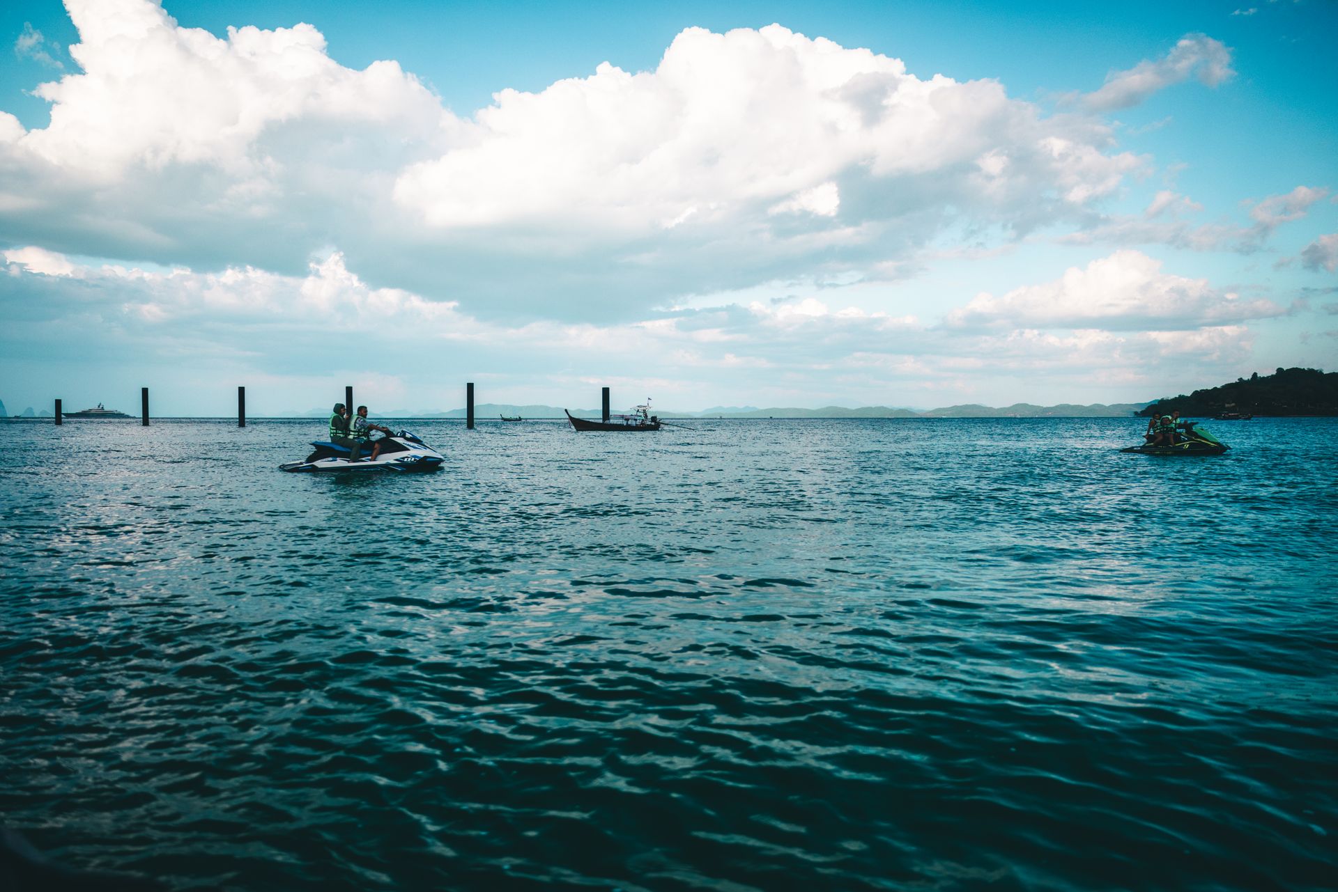 Experience the thrill of jet skiing on Phuket's vibrant blue sea under a vast cloudy sky.